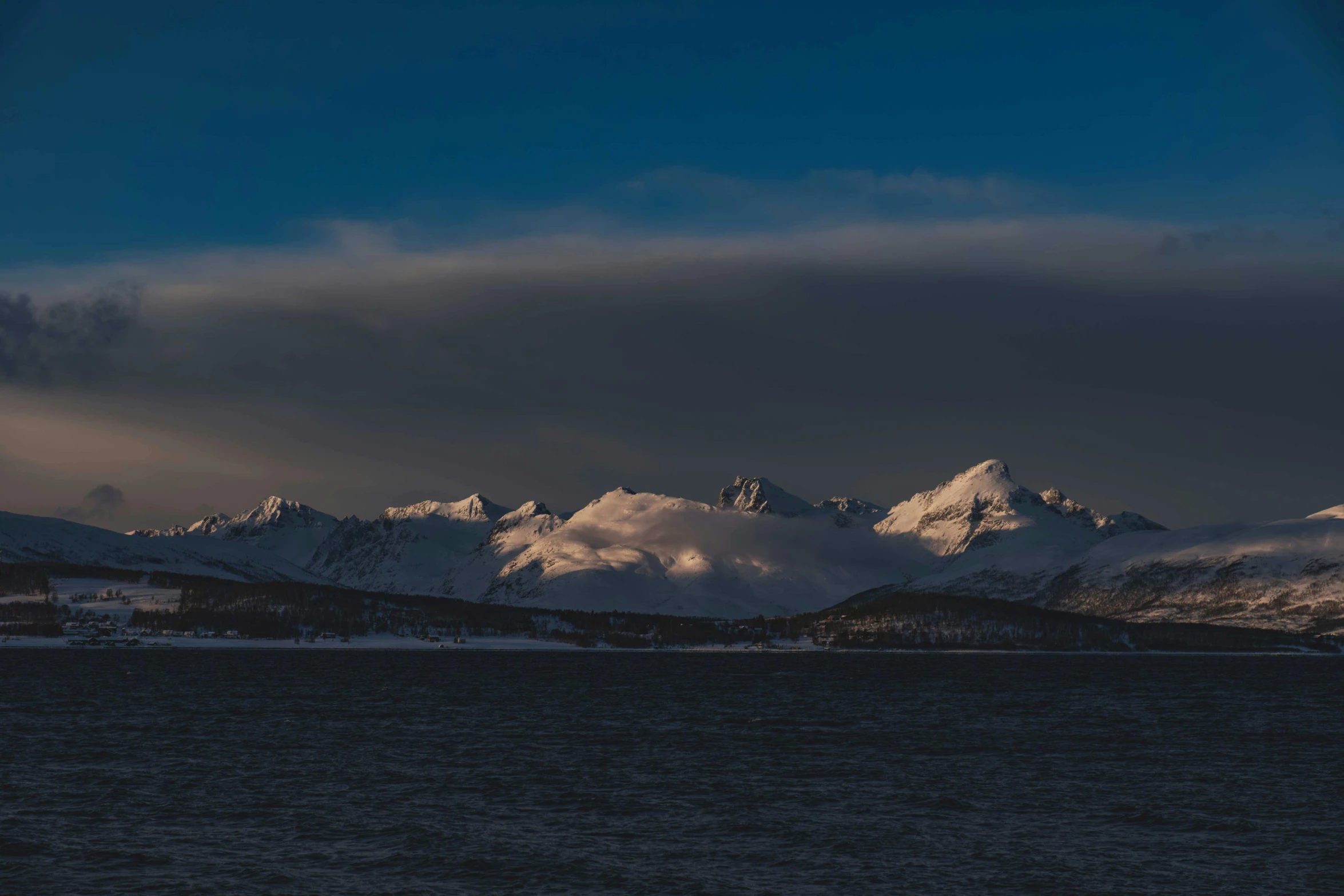 mountains and clouds above a body of water