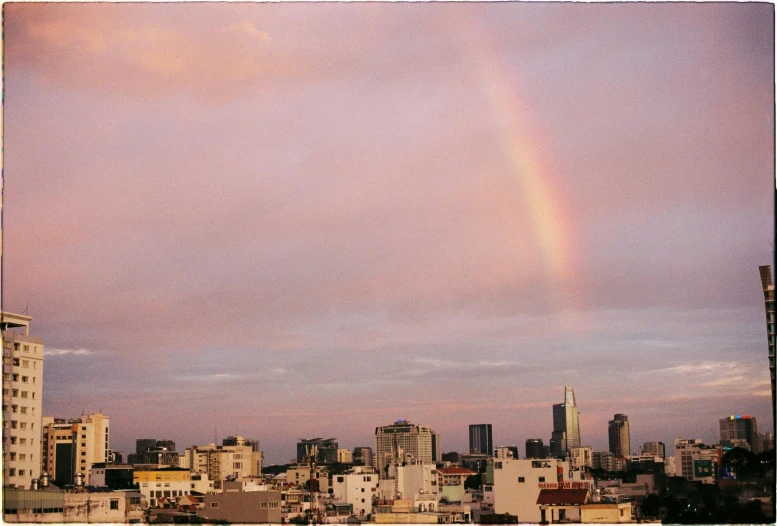 a rainbow appears over a city with tall buildings