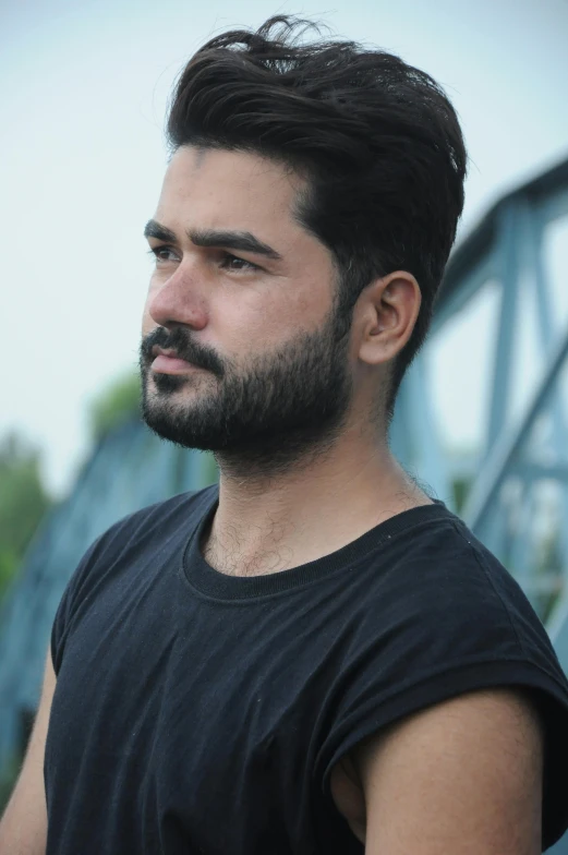 man with beard and beard standing outside in front of bridge