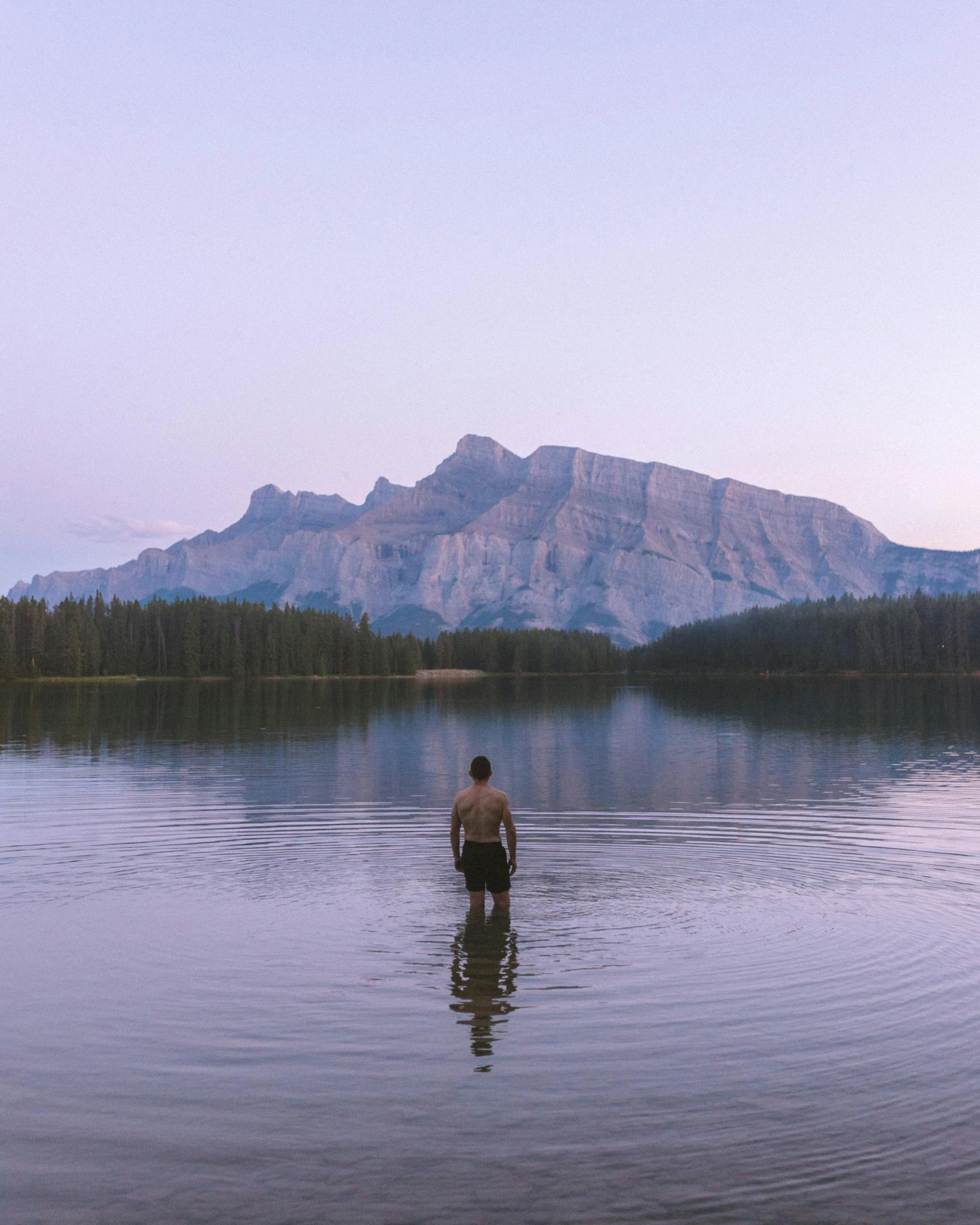 a man wading in the lake during sunset