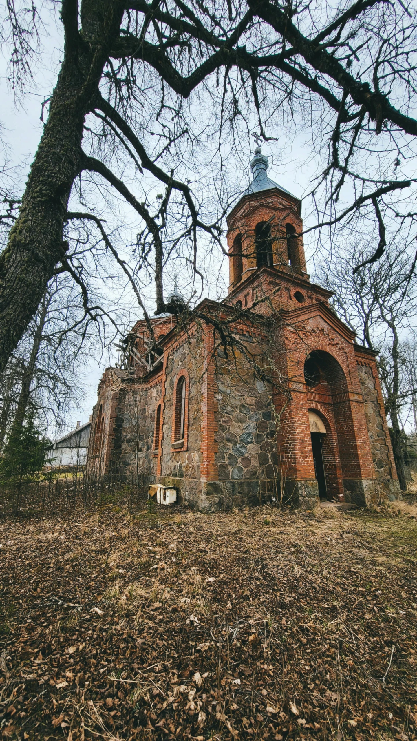 an old, very faded looking church by a bare tree