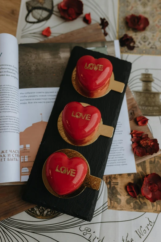 there are red hearts on the table next to a book