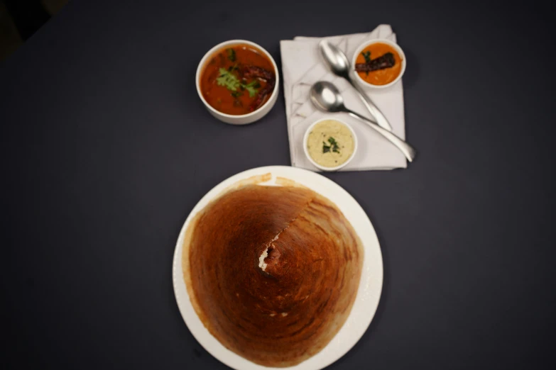 three bowls of soup sitting on a black table with silverware