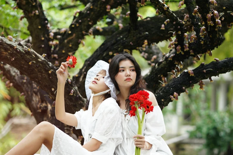 two women dressed in white are posing for the camera with their bouquet