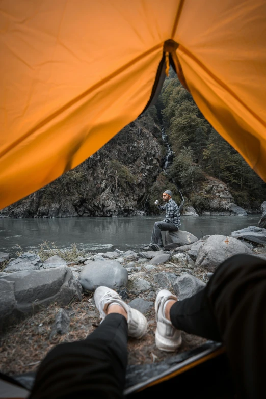 a man sitting inside of a tent on top of a river