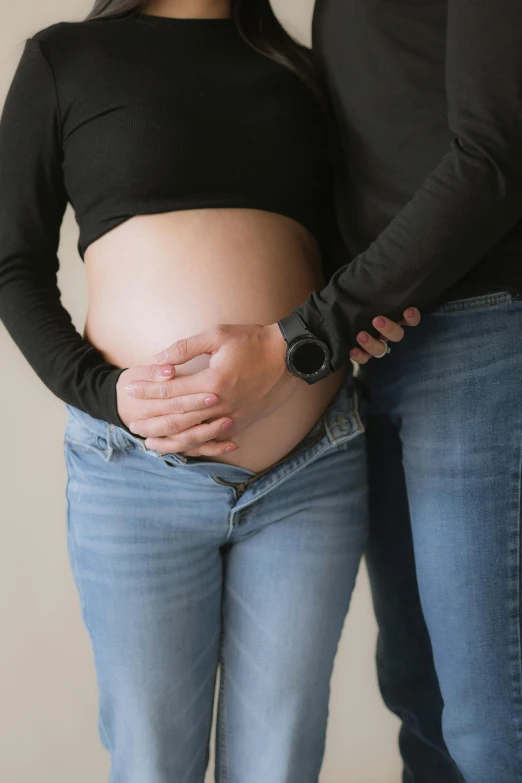 a pregnant woman holding her belly in her husband's arms