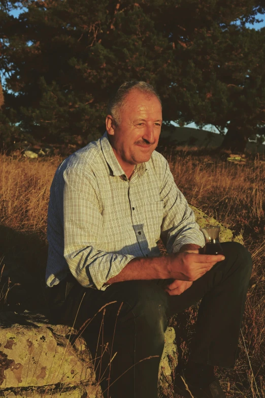 a man sitting down in the grass holding soing