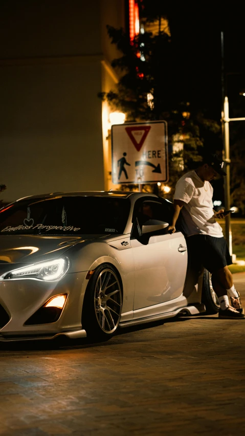 two people in hoodie sitting near a car