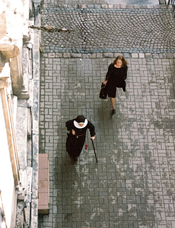 two people walking down a stone sidewalk together