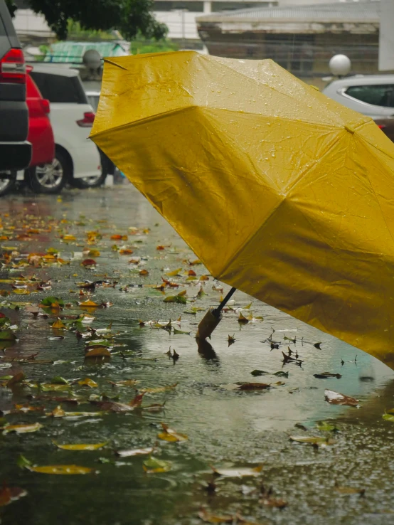 a large yellow umbrella floating in the air on a wet street