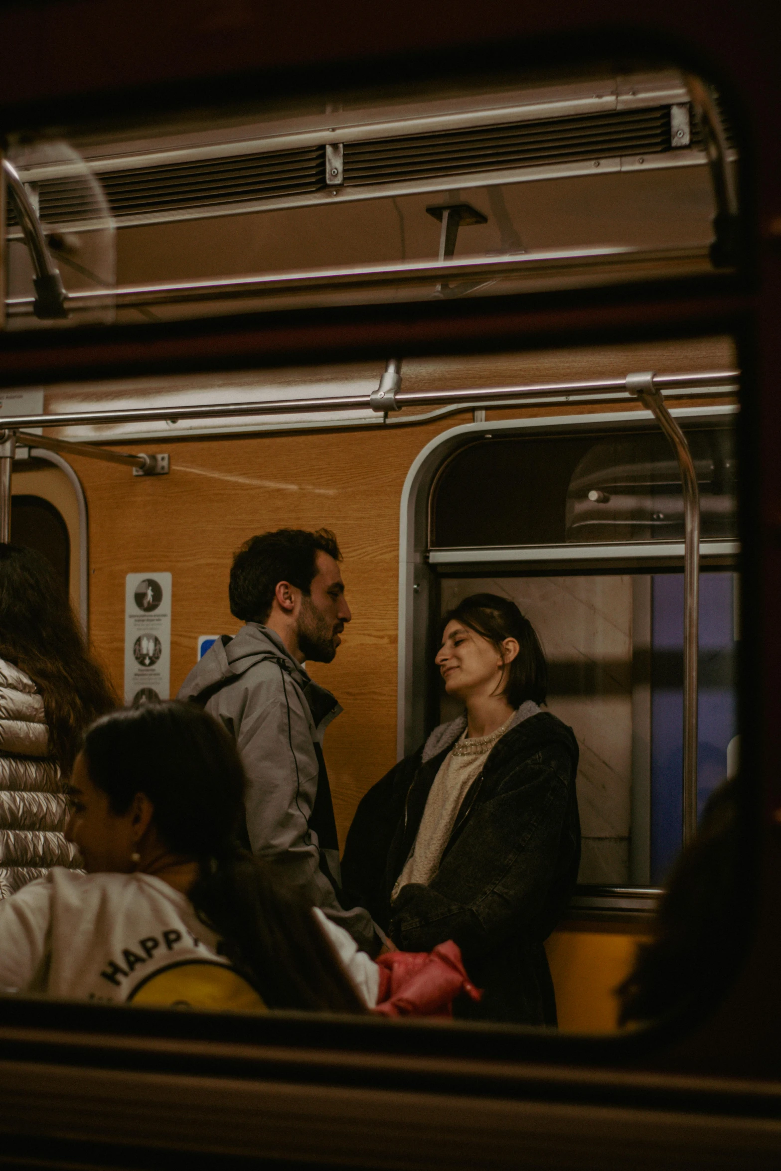 several people on a subway train with a man standing