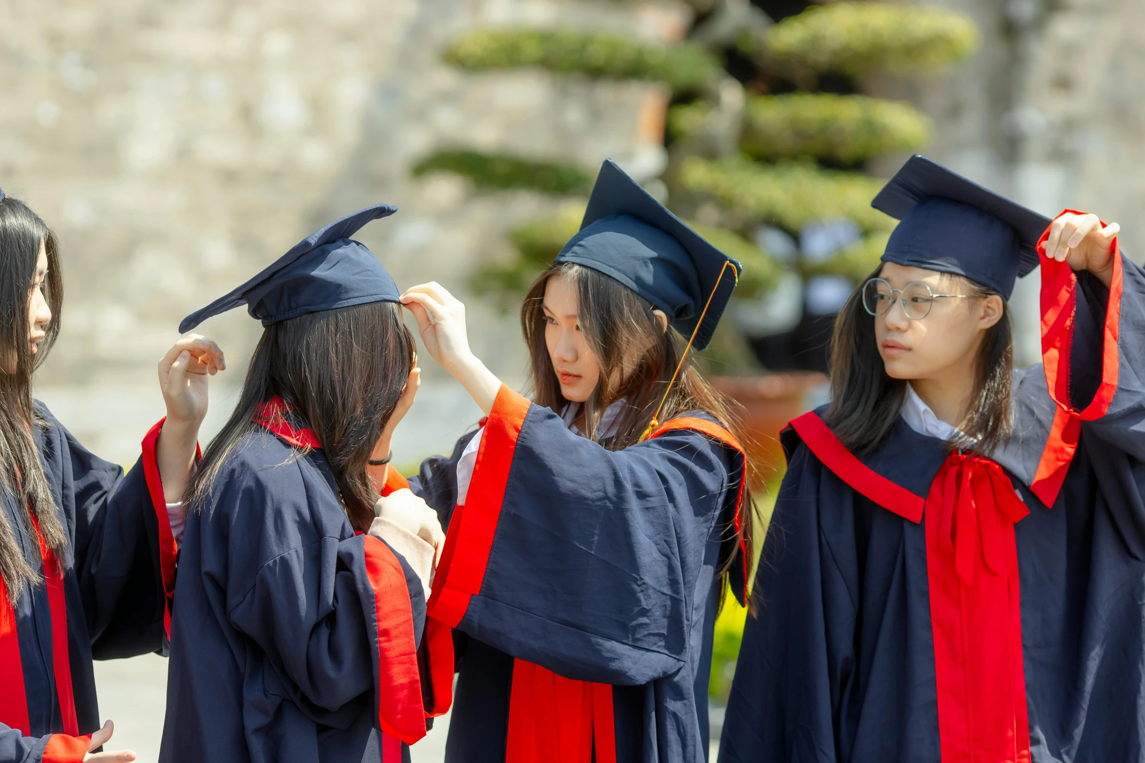 three students in graduation robes stand together