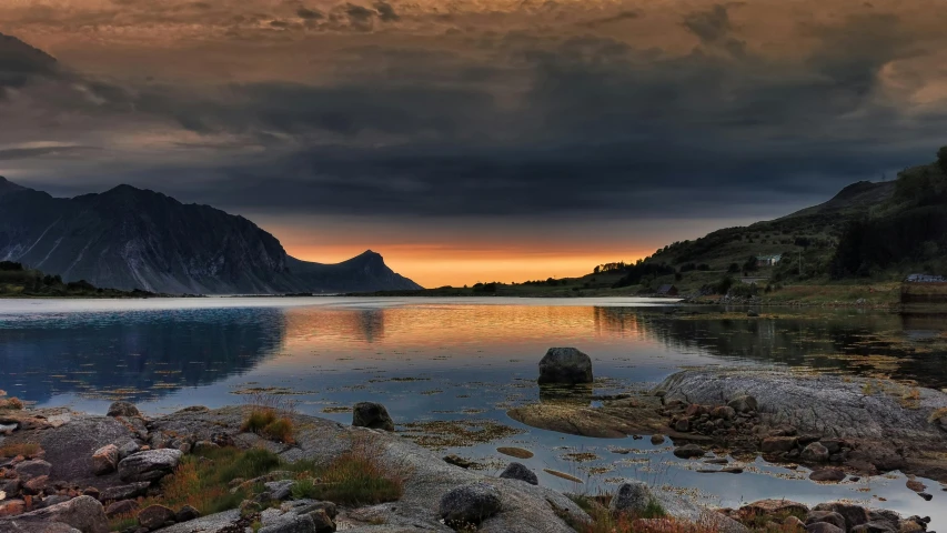 a body of water surrounded by mountains with rocks in it