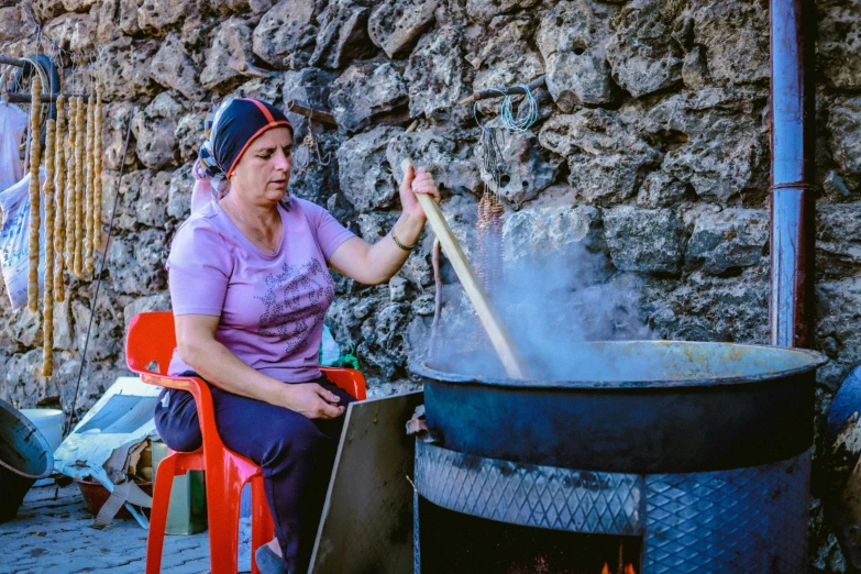 a woman cooking a pan over an open fire pit