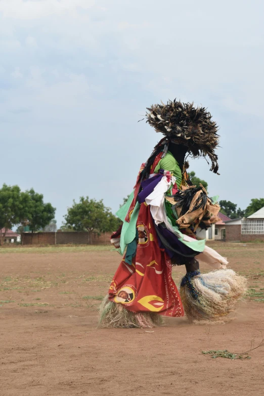 woman walking across dirt field carrying hay and a wreath