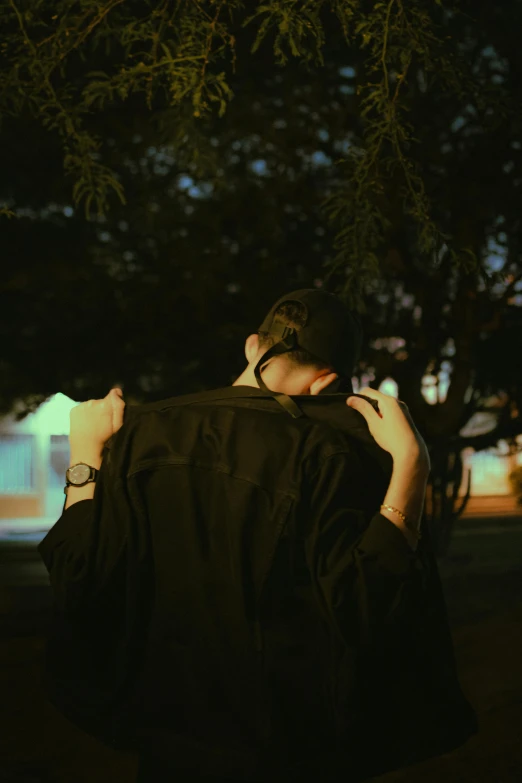 a young man is wearing a black jacket and he is holding his collar