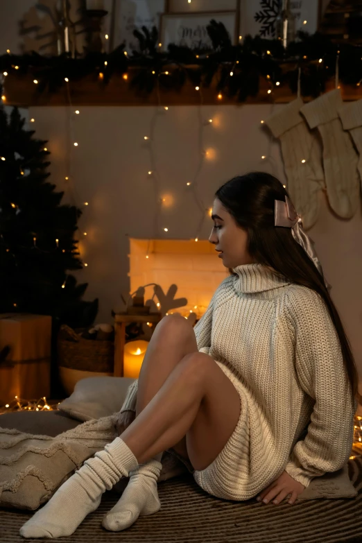 a beautiful woman sitting on top of a bed next to a christmas tree