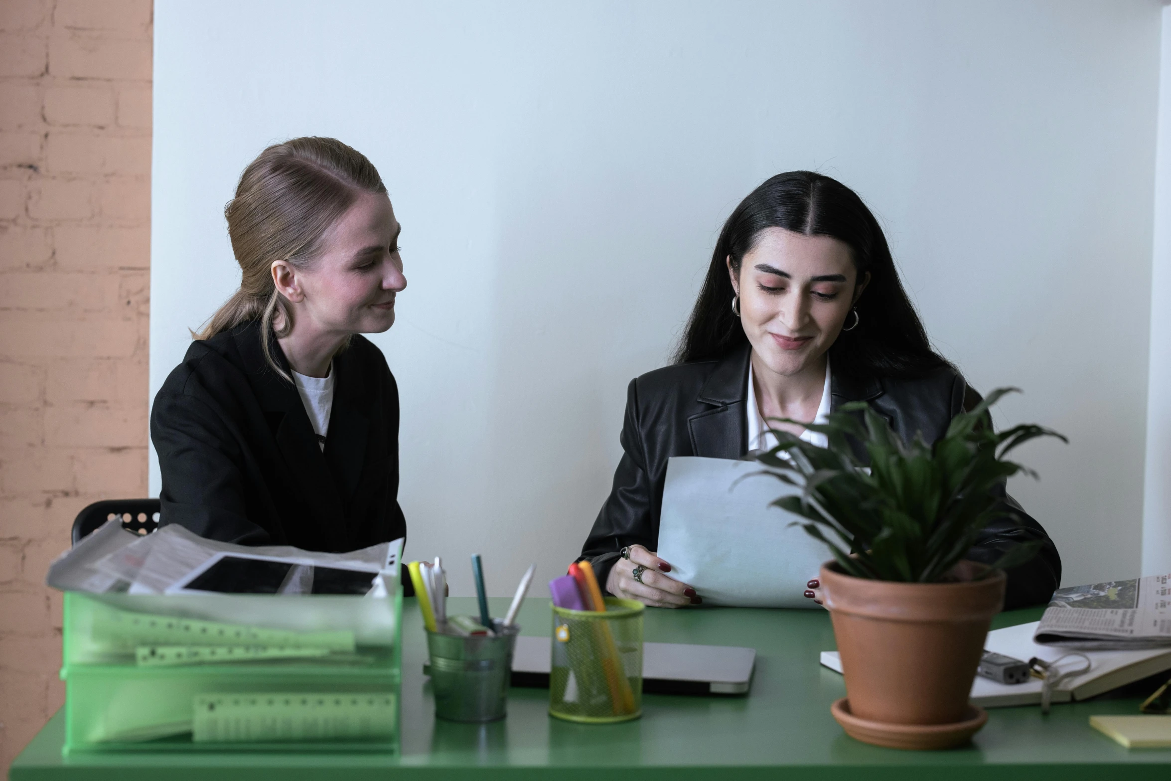 two women sitting at desk with books and papers