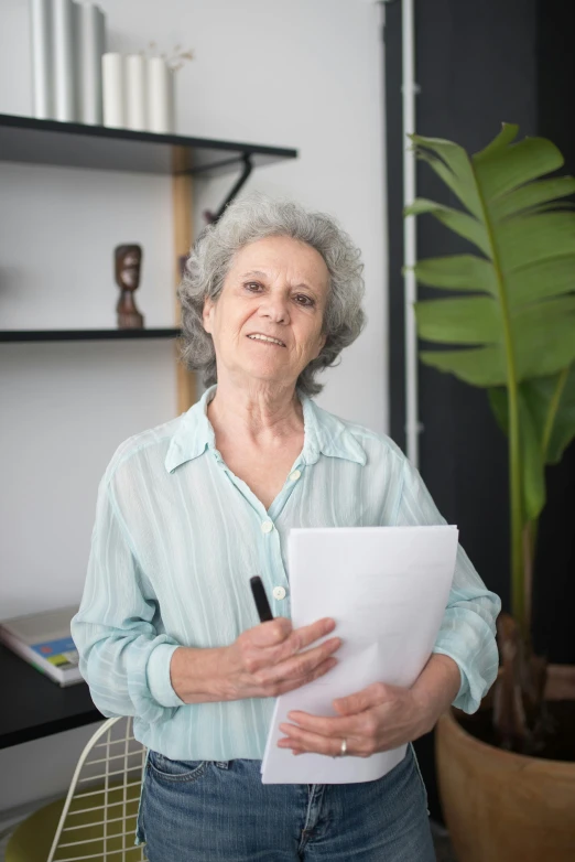 a woman in a blue shirt is standing with a notepad