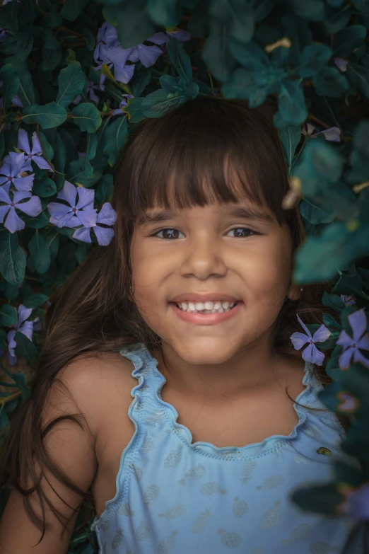 a little girl is posing with purple flowers