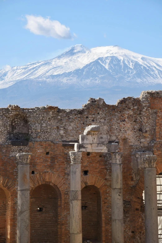 an old brick and stone building with a snowy mountain in the background