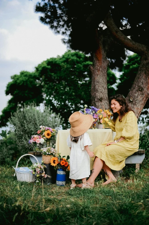 two women sit on a bench, a table and flowers