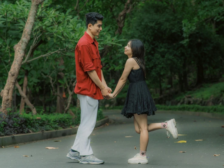 man and woman holding hands walking in front of trees