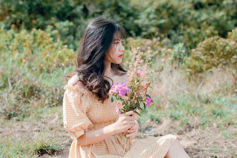 a woman sitting on the ground with a bouquet of flowers in her hands