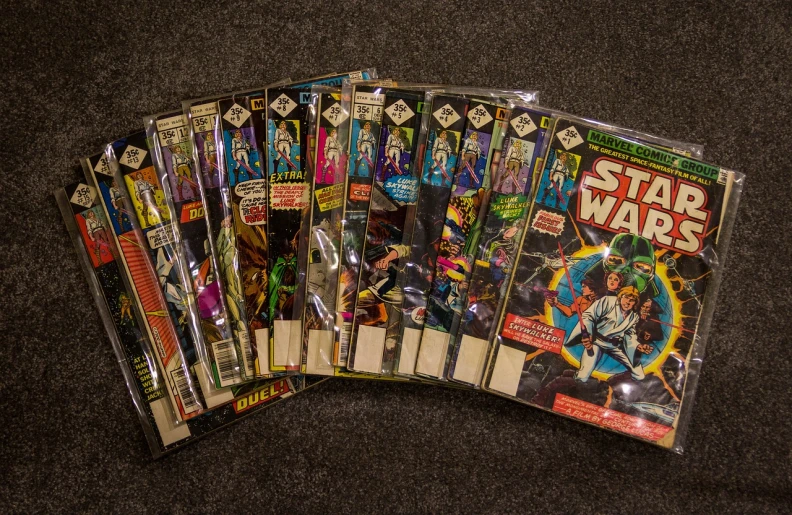 a bunch of comic books sitting on top of a table, a photo, inspired by Dave Gibbons, flickr, star wars expanded universe, for 1 9 7 0 s'sci - fi, soft lighting sold at an auction, comic book cover style