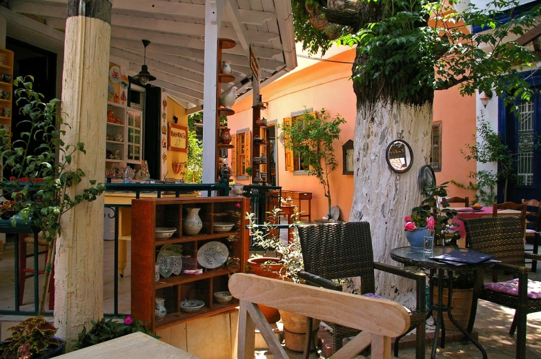 a patio with tables and chairs under an umbrella, a picture, inside an old magical shop, olive tree, house kitchen on a sunny day, tangelos