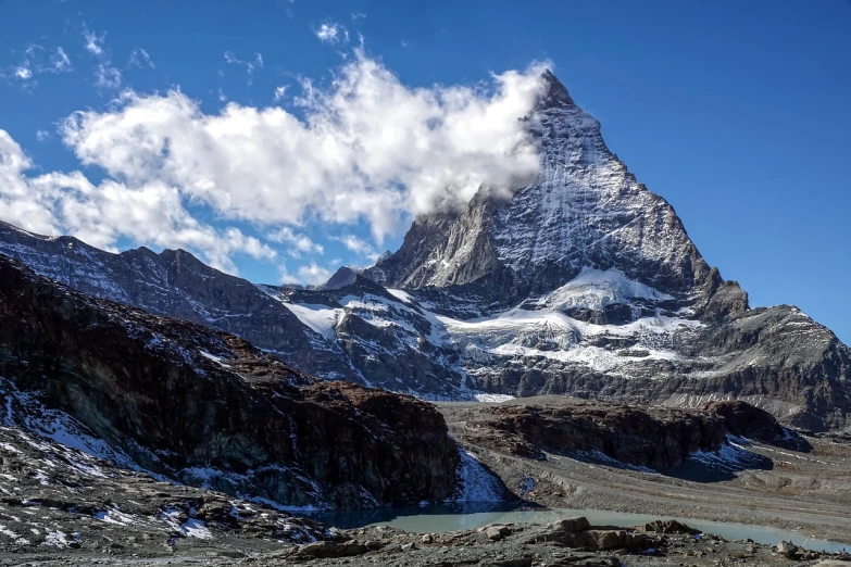 a mountain covered in snow next to a body of water, by Werner Andermatt, giant imposing mountain, heaven in the top, rocky foreground, very very very epic