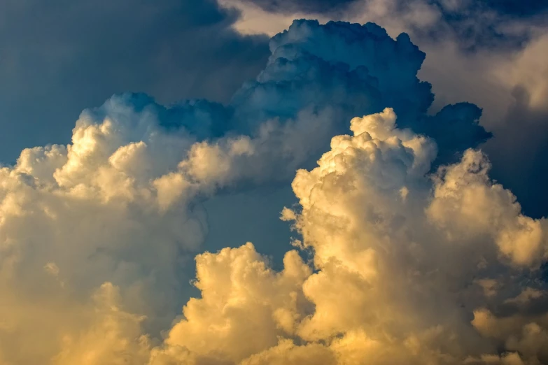 a jetliner flying through a cloudy blue sky, a stock photo, baroque, dramatic storm sunset, giant cumulonimbus cloud, bathed in golden light, hazy sunset with dramatic clouds