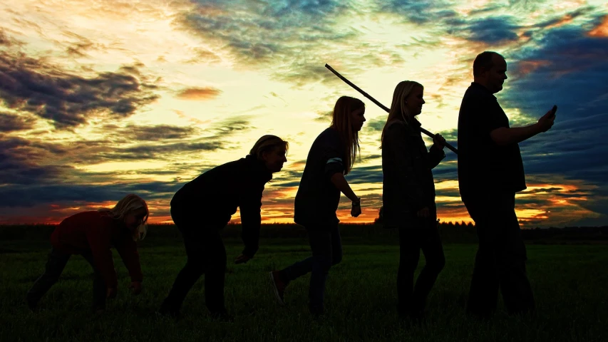 a group of people standing on top of a lush green field, by Jesper Knudsen, flickr, attacking with axe, at dusk, people's silhouettes close up, floggers