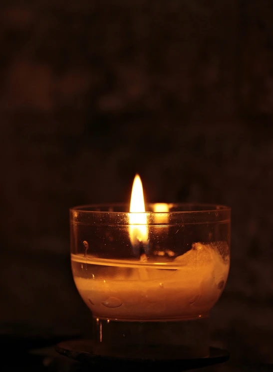 a lit candle sitting on top of a table, a picture, by Tom Carapic, full res, solemn, it is emitting a bright, candlelit catacombs