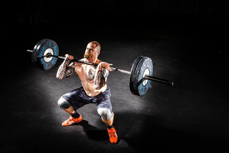 a man is doing a squat with a barbell, by Matt Stewart, pexels contest winner, figuration libre, tattooed man, high tech, split near the left, conor mcgregor