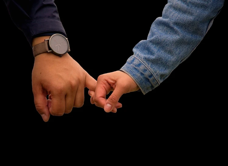 a close up of two people holding hands, a stock photo, by Jan Rustem, realism, on a flat color black background, watch photo, wearing jeans and a black hoodie, love peace and unity