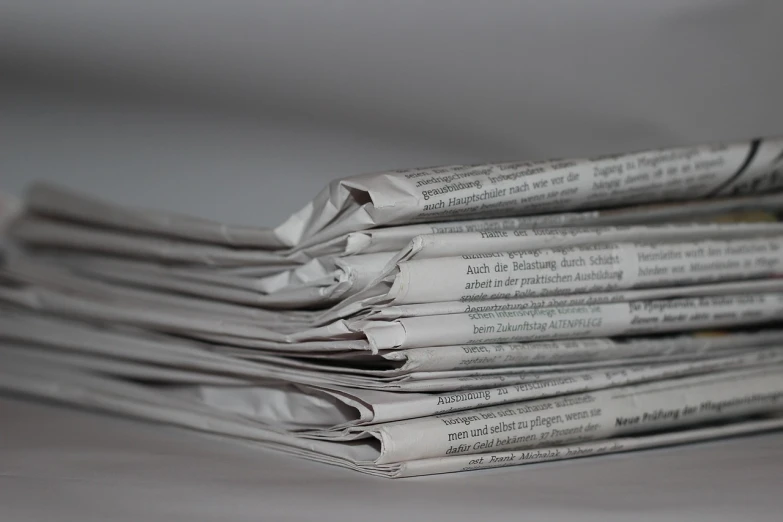 a stack of newspapers sitting on top of a table, by Matija Jama, private press, video, some wrinkled, behaelterverfolgung, close - up studio photo