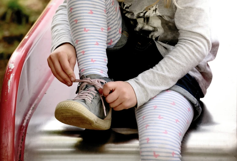 a little girl sitting on top of a slide, by Robert Brackman, pixabay, realism, striped socks, pink and grey muted colors, pulling strings, sneaker photo