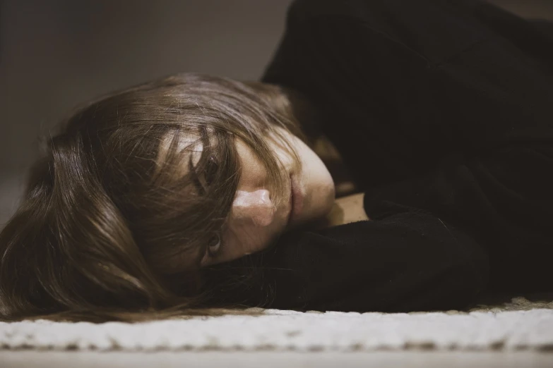 a little girl that is laying down on the floor, a picture, by Elsa Bleda, hurufiyya, woman very tired, girl with brown hair, with depressive feeling, profile picture