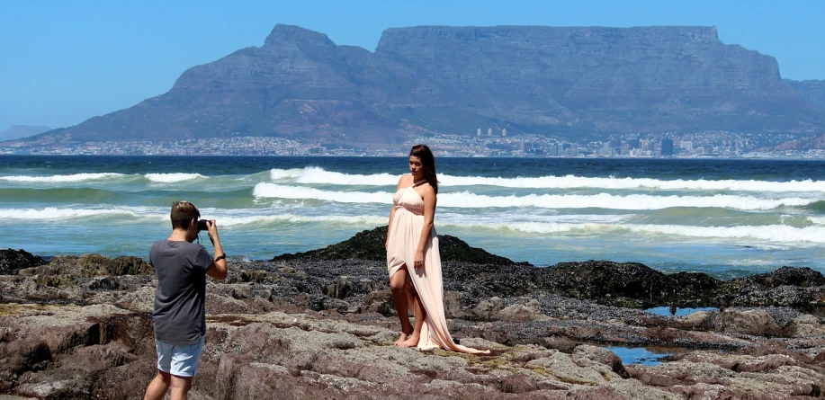 a man taking a picture of a woman on the beach, a picture, inspired by Arie Smit, haute couture fashion shoot, moutain in background, goddess queen, full body shoot