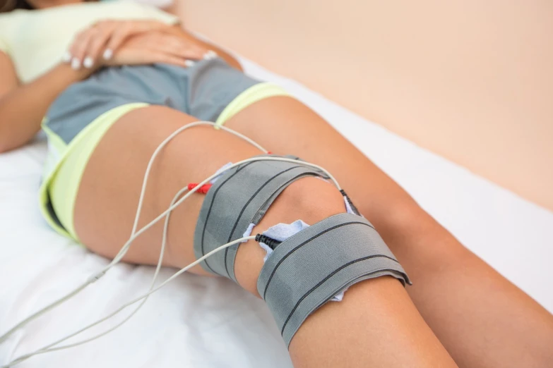 a close up of a person laying on a bed, a stock photo, by Adam Marczyński, shutterstock, cables on her body, knee, vitals visualiser!!, closeup photo