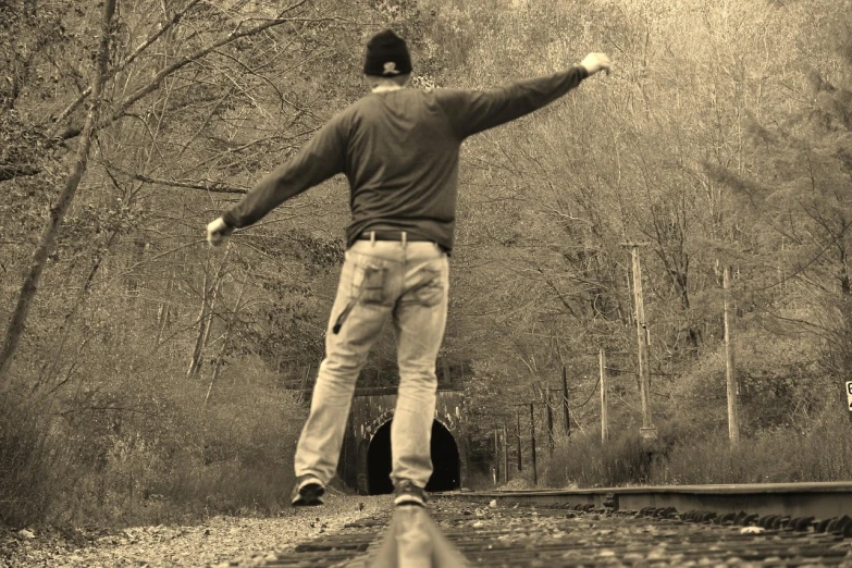 a black and white photo of a man throwing a frisbee, by Edward Corbett, pixabay contest winner, happening, rail tracks lead from the mine, full body sarcastic pose, sepia, light at the end of the tunnel