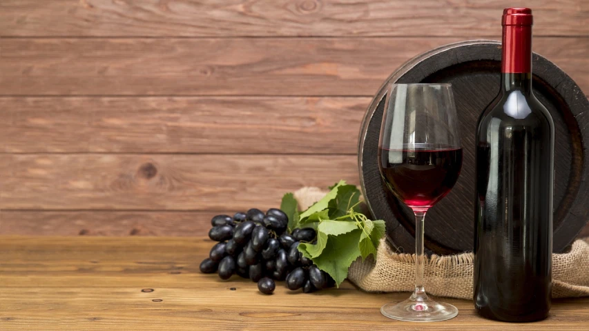 a bottle of wine sitting next to a glass of wine, a still life, shutterstock, grapes, 🕹️ 😎 🔫 🤖 🚬, a wooden, berry juice