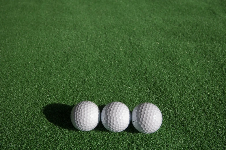 three golf balls sitting on top of a green field, inspired by Shirley Teed, 33mm photo