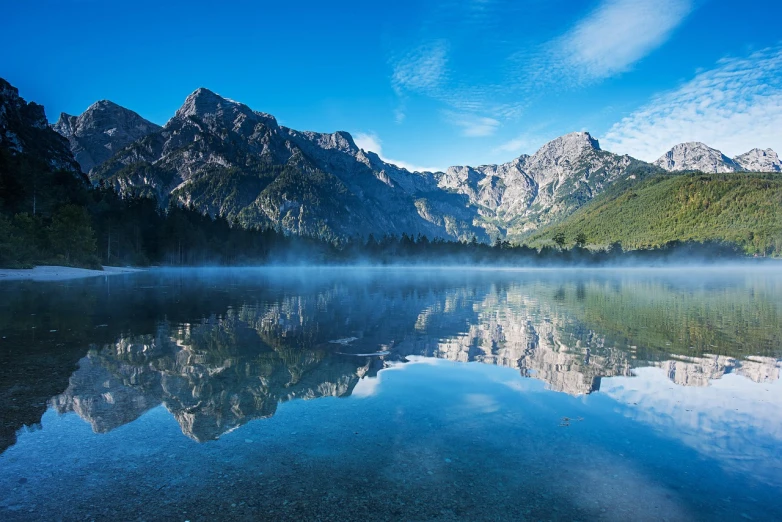 a body of water with mountains in the background, a picture, by Matthias Weischer, shutterstock, summer morning, perfect symmetrical image, mount olympus, morning mist