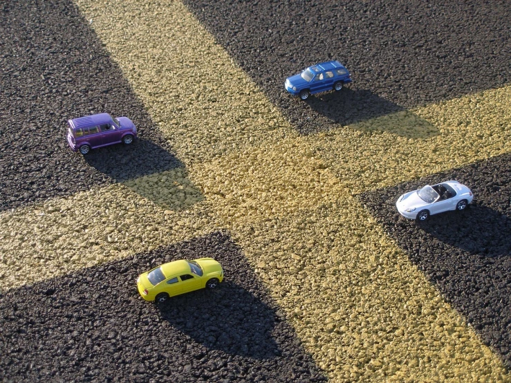 a group of toy cars sitting on top of a road, photorealism, hazard stripes, cross, winning, small