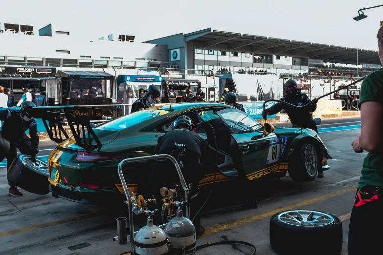 a man standing next to a racing car, by Matthias Weischer, pexels contest winner, dressed in a green robe, pits, a tvr sagaris, thailand