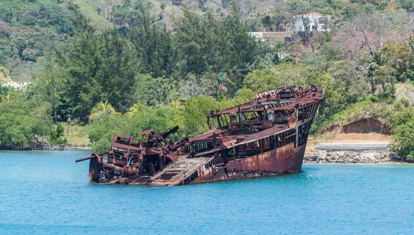 a rusted ship sitting in the middle of a body of water, by Richard Carline, jamaica, spoiler, abel tasman, destroyed