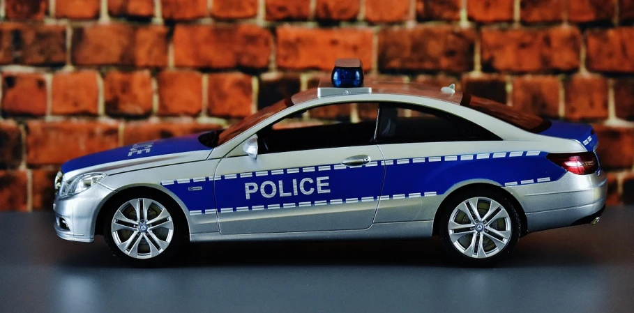 a toy police car sitting in front of a brick wall, by Thomas Häfner, pixabay, photorealism, mercedez benz, # e 4 e 6 2 0, with a roof rack, hsv