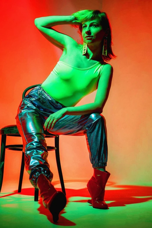 a woman sitting on top of a chair, a portrait, inspired by David LaChapelle, pexels, pop art, red and green lighting, glossy shiny reflective, portrait emily ratajkowski, studio!! portrait lighting